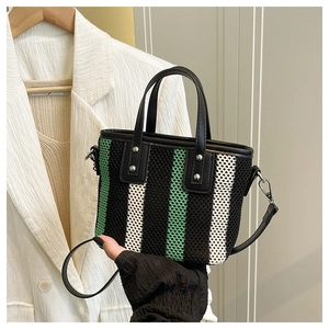Détail d'un sac seau tissé à rayures avec poignées en cuir et rivets métalliques