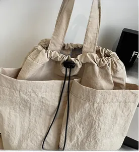 Detail of minimalist beige tote bag with drawstring closure and large exterior pockets
