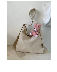 Detail view of khaki canvas tote bag with a pink plush bunny charm and textured fabric