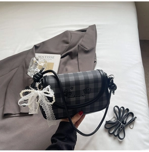 Detail of checkered shoulder bag with pearl chain, lace bow and chic embroidery