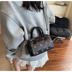 Detail of dark brown Boston bag with elk print worn by model in a modern interior