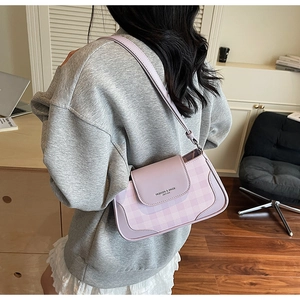 Détail du sac bandoulière à carreaux lavande porté par un mannequin dans un bureau