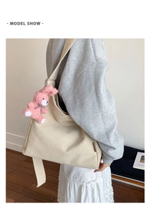 Detail of off-white canvas tote bag with a cute pink plush bunny charm on the strap