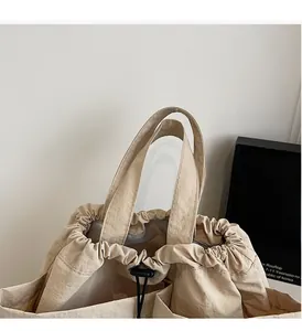 Detail of beige drawstring handbag featuring natural crinkled fabric and sturdy handles