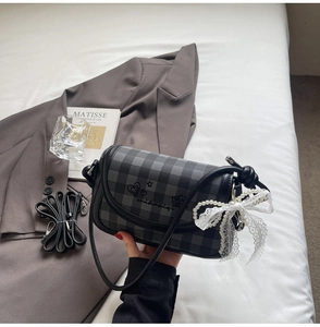 Detail of grey plaid flap bag with graffiti art and lace pearl bow charm accessory