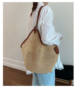 Detail of large woven straw tote bag with brown leather handles and mesh structure