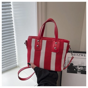 Détail du sac seau tissé à rayures rouges et blanches avec poignées en cuir et crochets