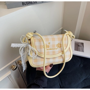 Close-up of checkered crossbody bag with gold embroidery, pearls, and lace bow details