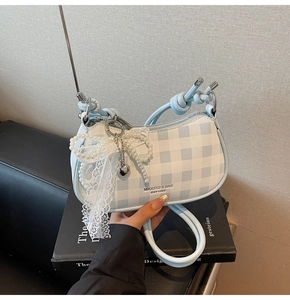 Détail du sac demi-lune à carreaux bleus avec nœud en dentelle de perles et pendentif cœur