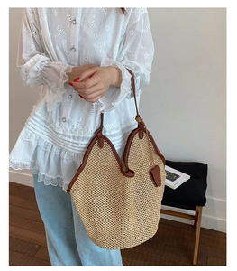 Detail of hand-woven straw tote with premium brown leather handles and smooth texture