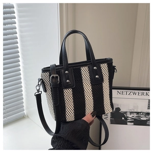 Détail du sac seau tissé rayé avec poignées en cuir et accents de rivets métalliques