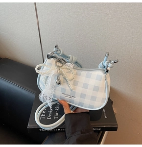 Détail du sac à carreaux bleu avec nœud en dentelle, perles et pendentif cœur