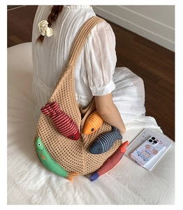 Detail of knitted beige tote bag featuring colorful 3D fish ornaments and wide shoulder strap