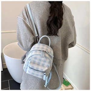 Détail du mini sac à dos à carreaux bleus et blancs porté par un mannequin en tenue de sport