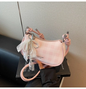 Détail du sac baguette rose à damier avec perles et breloque nœud en dentelle