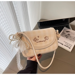 Detail of cream checkerboard crossbody bag with heart embroidery and pearl lace charm