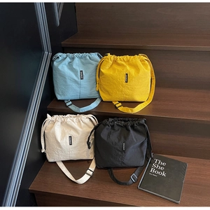 Detailed view of four drawstring bucket bags in blue, yellow, beige, and black colors