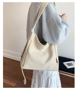 Close-up of a large beige canvas tote bag with thick texture and wide shoulder strap