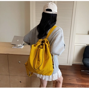 Detail of yellow nylon drawstring backpack with large front pocket for travel