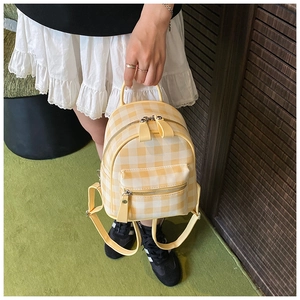 Détail d'un mini sac à dos à carreaux jaunes et blancs avec poche avant zippée