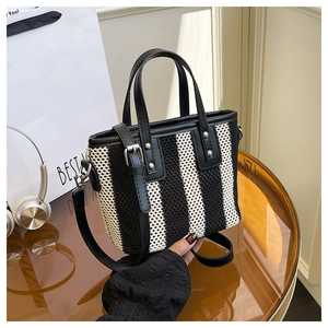 Détail du sac cabas tissé avec rayures noires et blanches et poignées en cuir