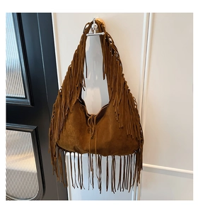 Detail of bohemian dark brown suede tote bag featuring long decorative fringe tassels
