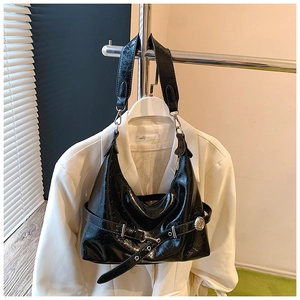 Detail of black patent leather hobo bag with pleated texture and metal buckle detail