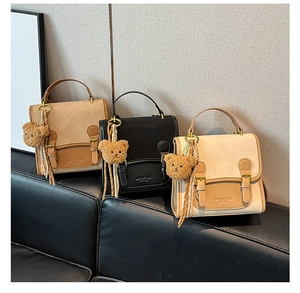 Detail of vintage patchwork leather handbags with dual buckles and plush bear pendant