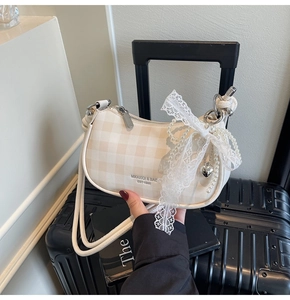 Détail du sac à bandoulière à carreaux avec nœud en dentelle et chaîne en perles