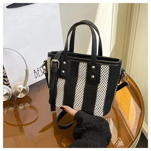 Détail du sac cabas tissé à rayures noires et blanches avec rivets et texture mesh