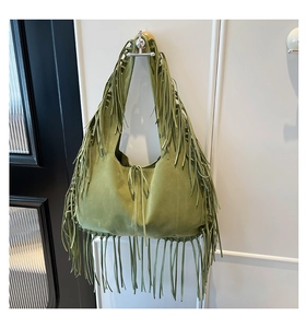 Detail of green suede hobo bag with fringe edges and bohemian tassel tassels on the strap