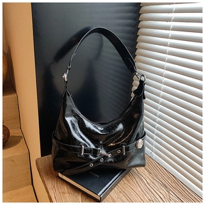 Detail of black glossy hobo bag with silver buckle and hardware on vintage book background