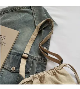 Detail of adjustable black buckle and long shoulder strap on a beige Oxford bucket bag