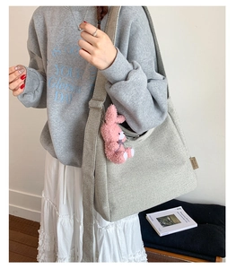 Detail of grey canvas tote bag with pink rabbit charm and wide adjustable shoulder strap