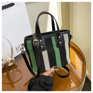 Détail d'un sac seau tissé tricolore avec poignées en cuir noir et rivets argentés
