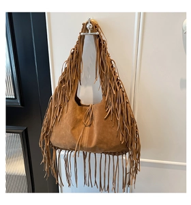 Close-up of brown suede hobo bag with long bohemian fringe hanging on a metal hook
