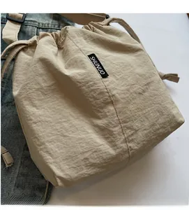 Detail of beige drawstring bucket bag featuring soft fabric and woven brand label