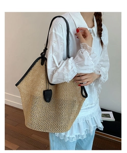 Detail of woven straw tote bag with black leather trim and long shoulder straps