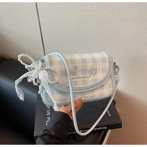 Detail of light blue checkered crossbody bag with pearl strap and lace bow accent