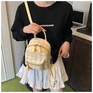 Détail d'un mini sac à dos à carreaux jaunes sur modèle montrant la taille