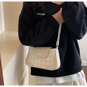 Dettaglio della borsa a tracolla beige a scacchi con patta in pelle e scritta moda