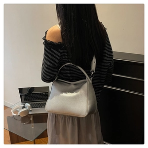 Detail of silver pebble grain leather handbag shown in a modern lifestyle setting