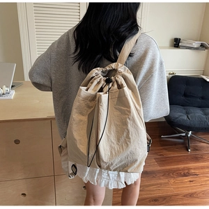 Close-up of lightweight beige drawstring backpack with Studio label and fabric texture