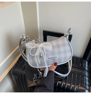 Détail du sac demi-lune à carreaux gris avec breloque perle et nœud en dentelle
