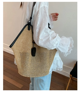 Large straw tote bag with black leather trim worn by model for a summer look