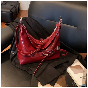 Detail of red patent leather hobo bag with adjustable metallic buckles on black leather