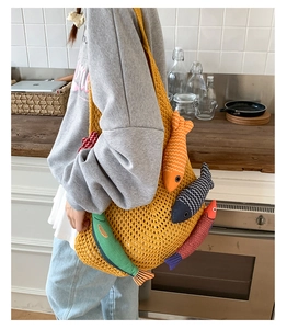 Close-up of a yellow woven tote bag featuring colorful fabric fish charms on chunky knit