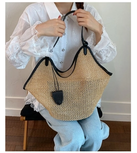Detail of straw tote bag with black leather trim and chic charms in a casual summer setting