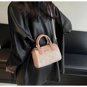 Close-up of pink Boston bag with deer print and metallic logo on black leather jacket