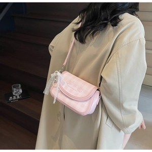 Close-up of pink checkered crossbody bag with lace bow and pearl heart charm detail